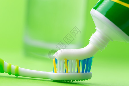 在绿色的牙刷上挤压牙膏的特写图片