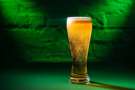 近视玻璃和新鲜的冰冷安柏啤酒在绿光中图片