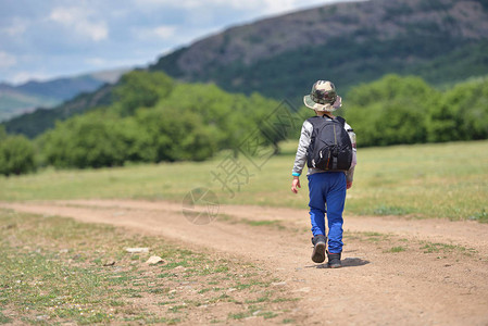 带着背包走在山上一条小路上的可爱男孩徒高清图片