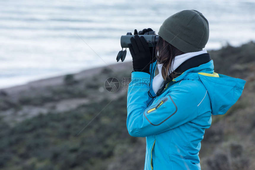 女孩用双筒望远镜从悬崖上看海图片