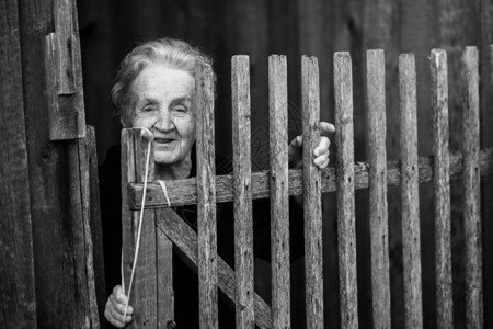 年长妇女站在村里的木栅栏后图片