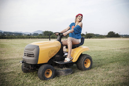 在田野里驾驶割草机的工作女孩图片