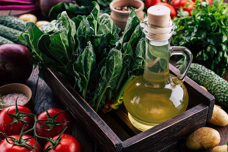餐桌上的木箱中菠菜蔬菜和植物油西红柿黄瓜和绿色图片