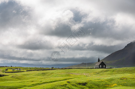 冰岛布迪尔山脉和暴风雨云前的黑色木制教堂图片