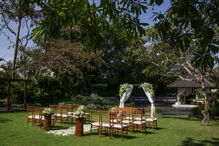 在热带花园木椅和用白色花朵装饰的简单观舞厅举行美丽浪图片