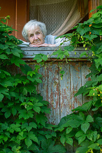 老年妇女坐在农村房子里的绿色阳台上Greente图片