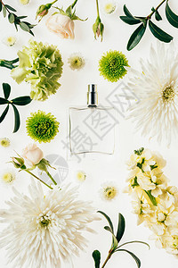 玻璃瓶香水的顶部视图四周有鲜花和绿色树枝图片