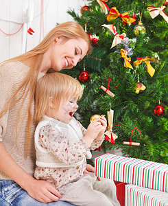 快乐的母亲与她的女儿在圣诞树下图片