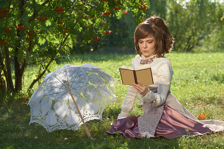 穿旧式服装的女孩在公园读书旁边有太阳图片