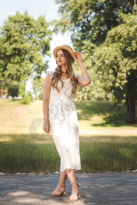穿着白色衣服和草帽的漂亮女孩站在草地上图片