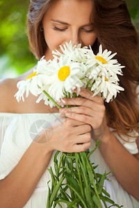 美丽的女人闻着一束花的香味图片