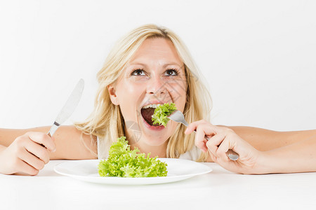 吃绿色沙拉吃饭的快乐女人的画像图片