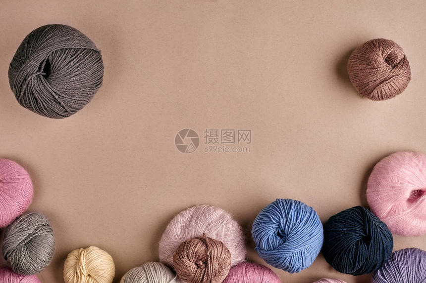 米色背景上的彩色羊毛纱组针织作为一种针线活五颜六色的毛线球和织针顶视图静物复图片
