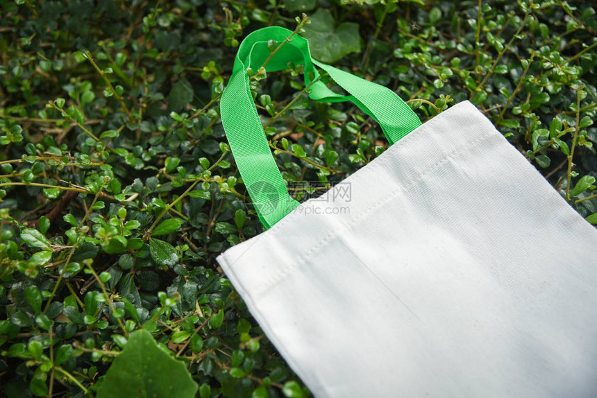 绿叶自然背景下的白色手提帆布面料生态袋布购物袋零废物使用少塑料袋图片