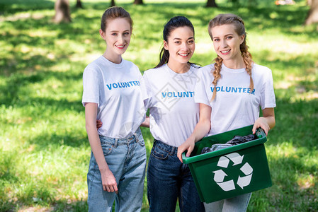 青年志愿者配有垃圾绿色回收箱图片
