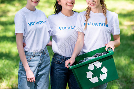 绿色回收箱中年轻女志愿者的图片