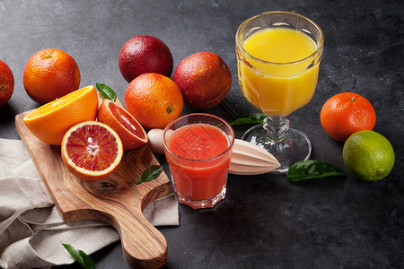暗石本底的新鲜柑橘和果汁图片