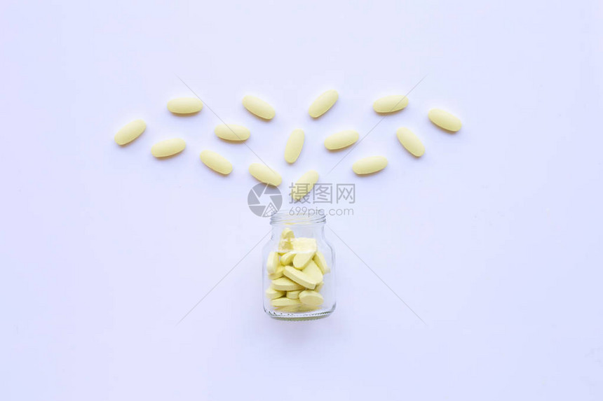维生素C瓶和白色背景上的药丸图片