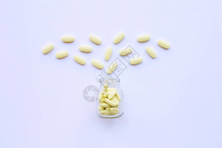 维生素C瓶和白色背景上的药丸图片