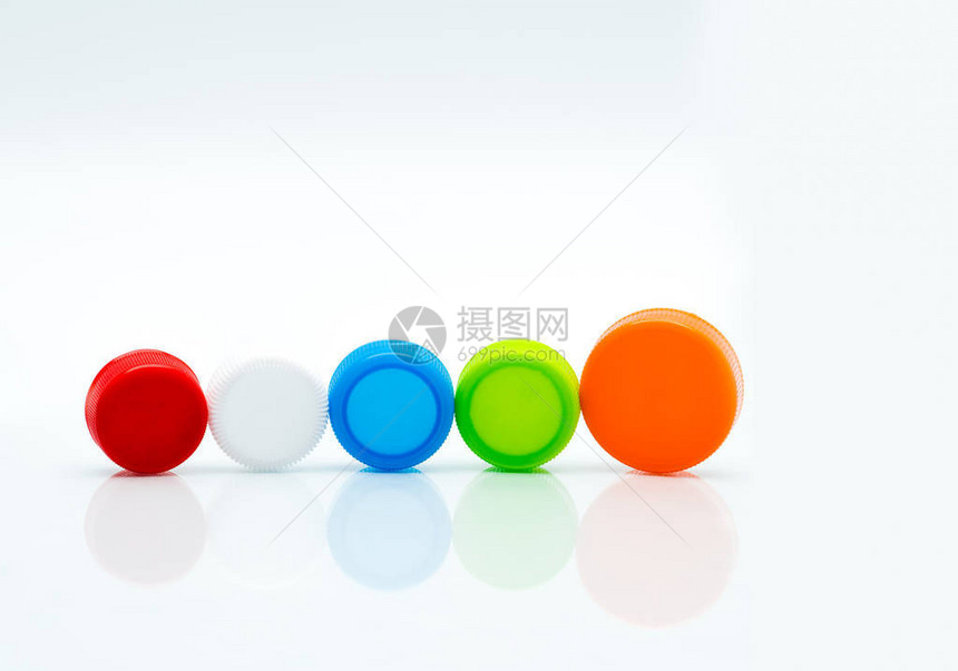 不同尺寸的白色绿色红色蓝色和橙色圆形塑料螺帽在白色背景和复制空图片