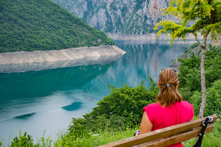 女孩在山湖岸边的长椅上休息图片