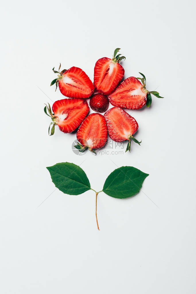 用草莓切片和白绿叶制成的花朵的顶视图图片