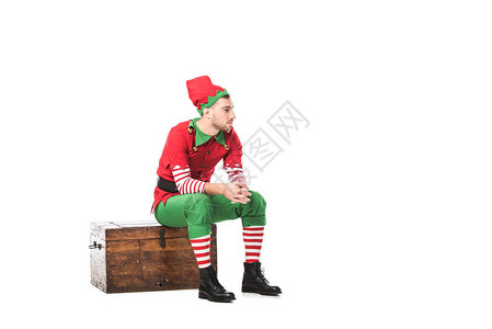 穿着圣诞精灵服装的人坐在木制胸膛上图片