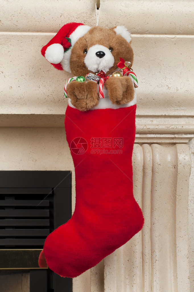 一只棕色泰迪熊挂在红色圣诞长袜上图片