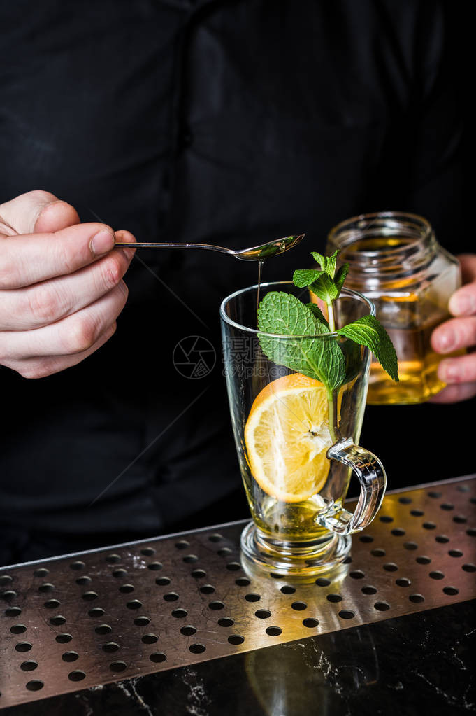 酒保在深色背景的玻璃杯中准备带有蔓越莓的水果茶图片