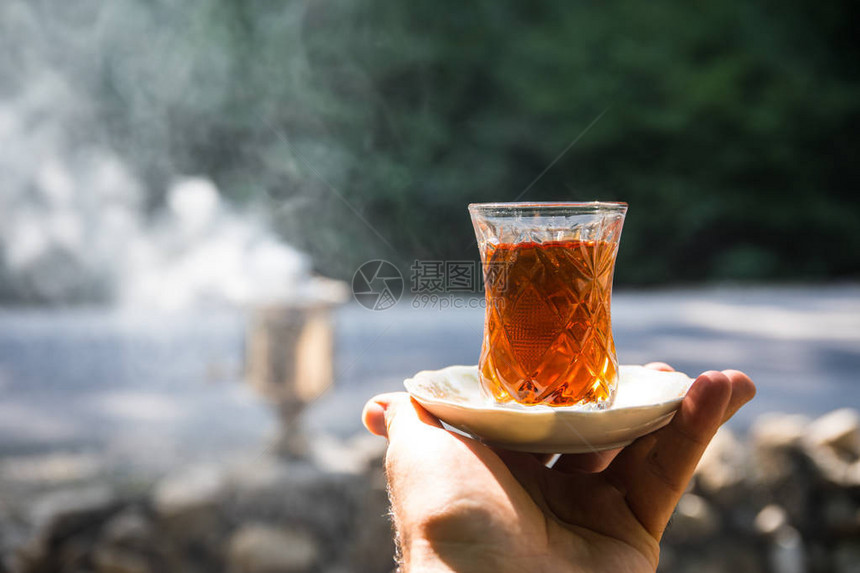 东方红茶在森林里女人手上的玻璃杯中东方茶概念Armudu传统杯绿色自然背景图片