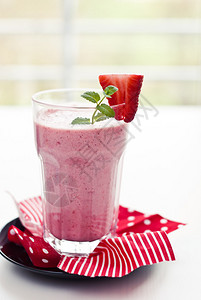 在白色背景上装饰着草莓的玻璃杯中的草莓奶昔图片