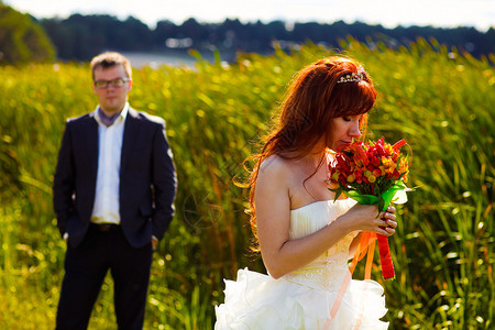 红头新娘在婚礼花束上闻着鲜绿草图片
