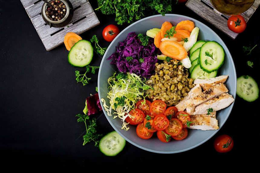 健康沙拉配鸡肉西红柿黄瓜生菜胡萝卜芹菜红卷心菜和绿豆在深色背景上适当的营养饮食菜单图片