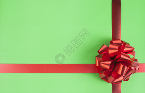 绿纸上的红色礼品弓和丝带背景图片