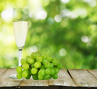 木制桌上的葡萄葡萄酒杯和酒瓶其背图片