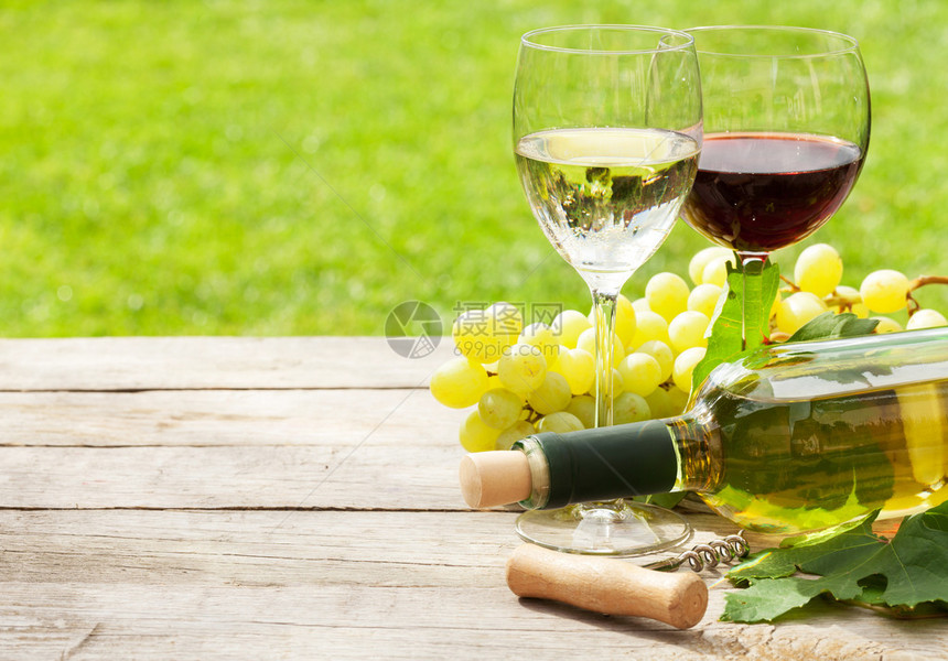 白酒和红酒杯酒瓶和白葡萄放在木桌上图片