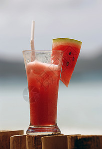 以大海为背景的西瓜汁玻璃杯图片