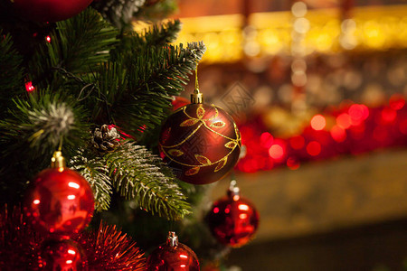 人造圣诞树装饰着丰富多彩的明亮球在模糊的红色上图片