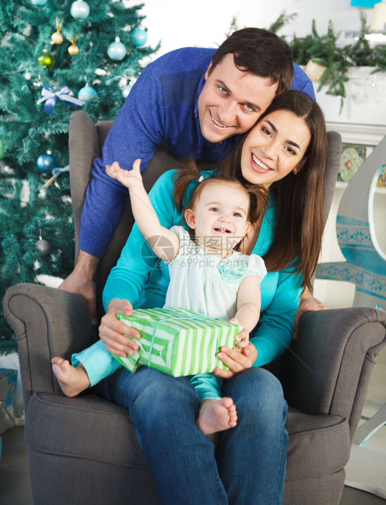 家庭快乐圣诞礼物在圣诞树旁边图片