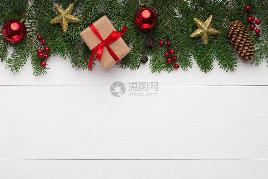 圣诞装饰品白色木质背景上带红球金星和礼盒的绿色杉木顶视图片