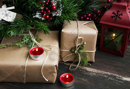 圣诞礼物在圣诞树下与红烧蜡烛和绿灯图片