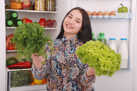 健康饮食概念饮食美丽的年轻女孩靠近冰箱与健康食品冰箱里的水果和蔬图片