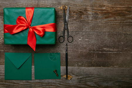 平躺着用红丝带剪刀和信封包裹的圣诞礼物图片