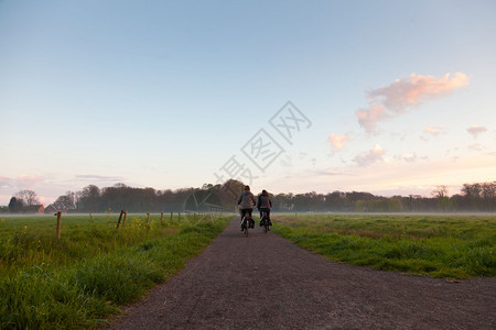 游客在路上骑车穿过草地在日落图片