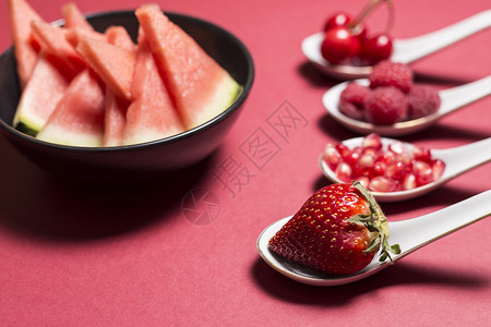 粉红色背景上勺子上的水果图片