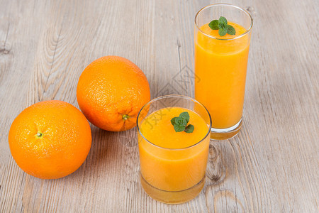 新鲜的橙子和生姜冰沙饮料木质背景图片
