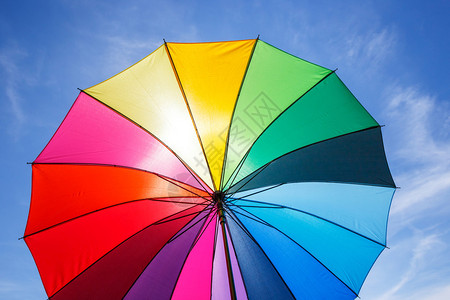 蓝色天空背景上彩虹伞的开图片