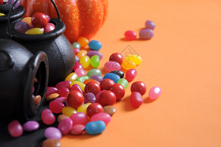 万圣节快乐的糖果在戏法或治疗中随身带着魔帽和橙色背景的果汁图片