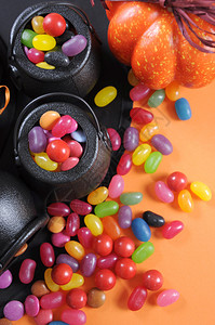 万圣节快乐的糖果在戏法或治疗中随身带着魔帽在橙色背景图片