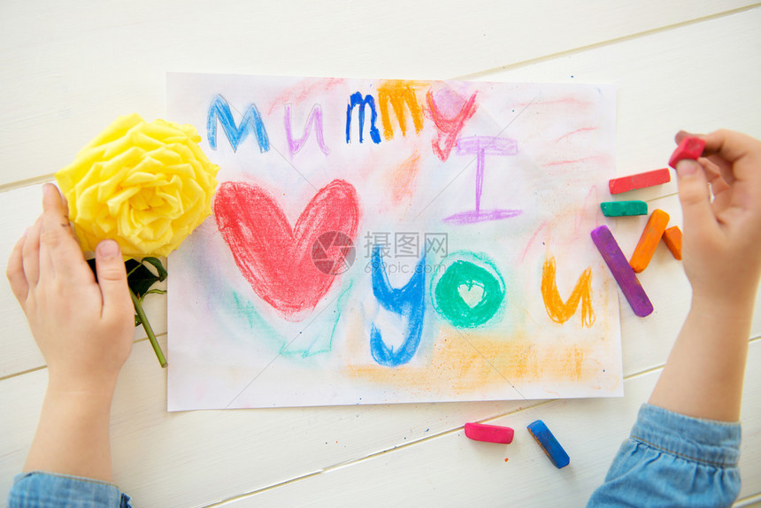 小女孩正在为母亲节用粉笔画明信片她写了妈我爱你黄图片